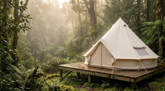 Canvas bell tent pitched in misty forest with ventilation flaps open to prevent humidity buildup