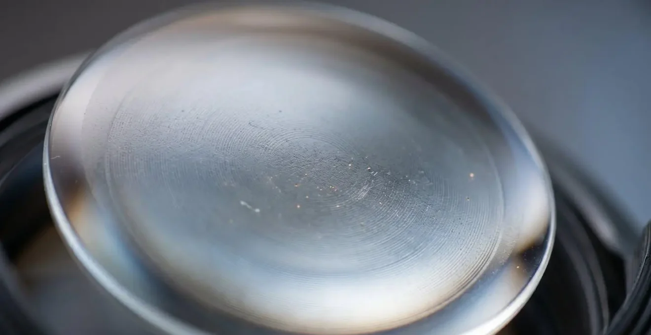 Extreme macro close-up of a camera lens glass element showing optical surface texture and coating layers
