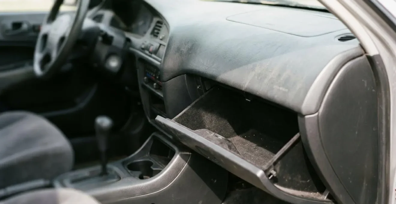 Car interior with open glove compartment and center console showing empty spaces as theft deterrent