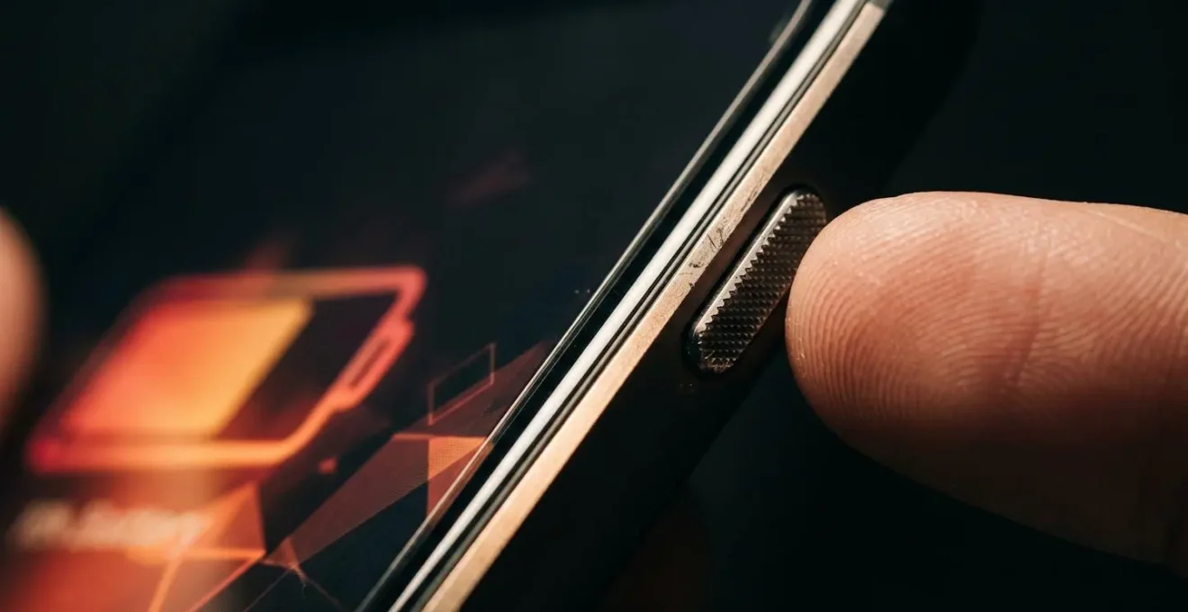 Close-up of smartphone displaying battery optimization settings with GPS icon visible in low-light conditions
