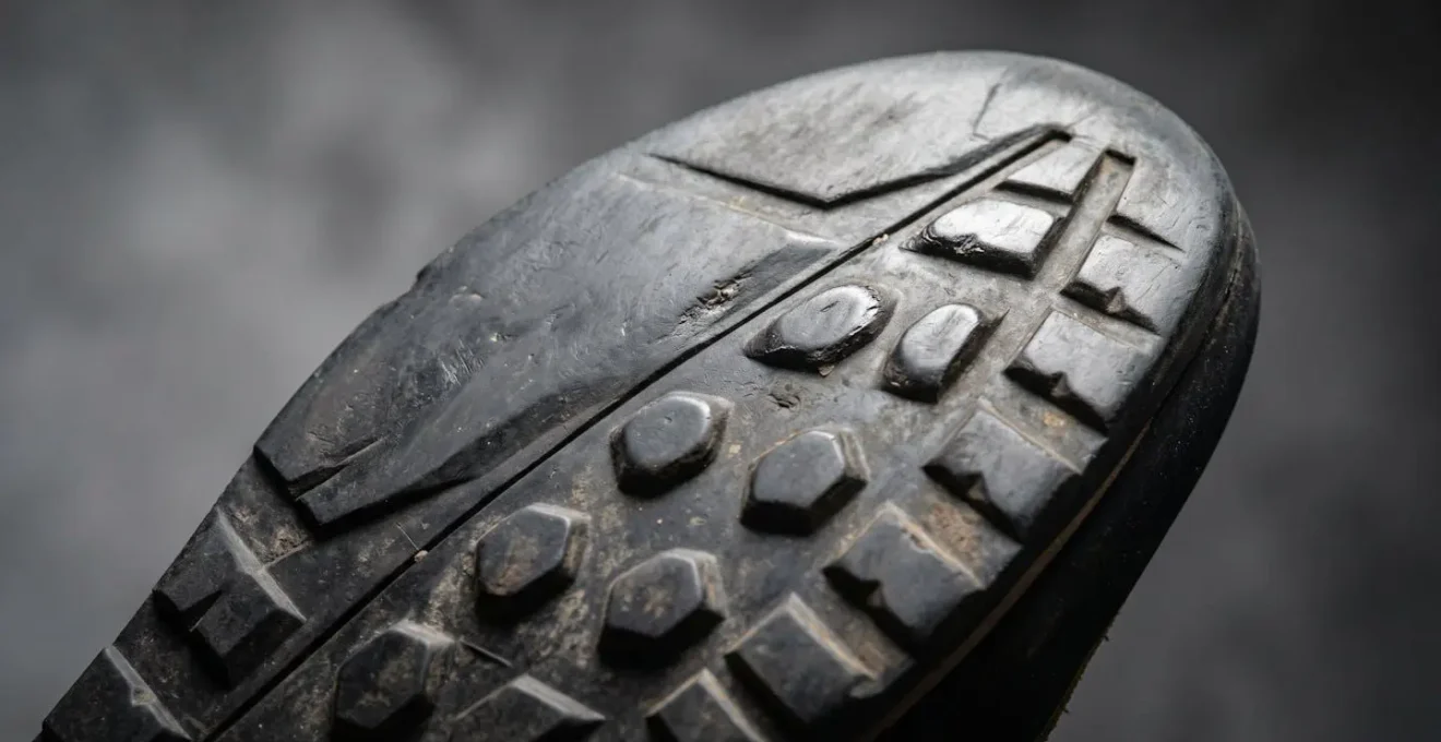 Macro detail of approach shoe outsole showing wear pattern on sticky rubber with rounded edges and polished surfaces