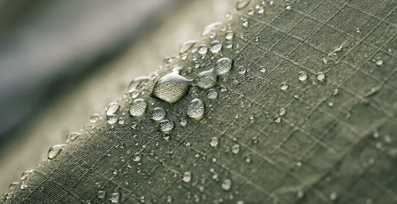 Close-up macro view of water condensation forming on tent fabric surface showing moisture physics