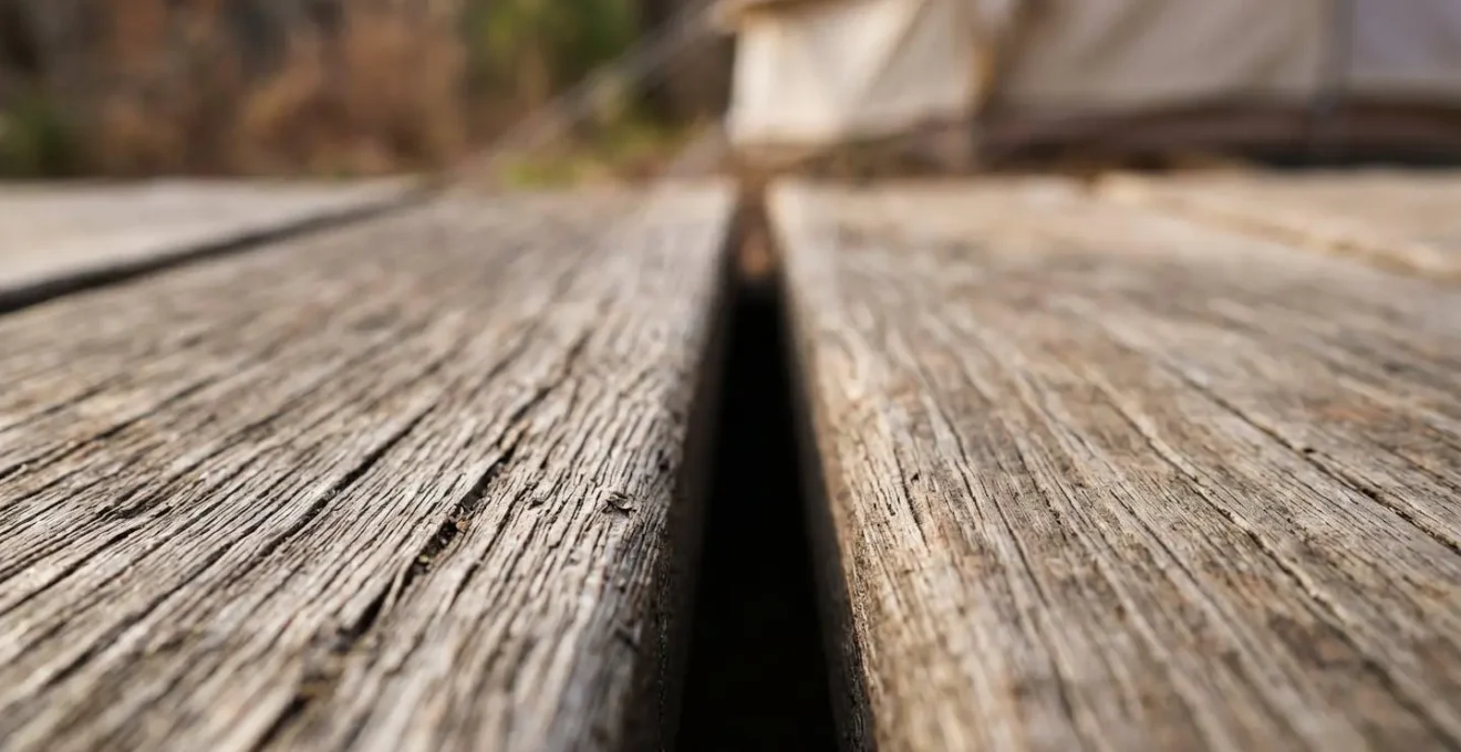 Close-up detail of wooden deck planks with quarter-inch spacing beneath canvas tent floor showing airflow gap